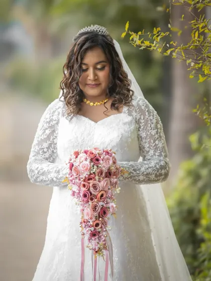 A beautiful solo portrait of the bride, looking down at her stunning cascading bouquet. The soft light and gentle pose create a serene and elegant image.