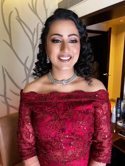 For a modern reception or cocktail party, we can create a glamorous look like this. I gave this client a radiant, dewy base with a soft smokey eye and a beautiful smile, paired with a modern off-shoulder gown and diamond jewellery. Her natural curls were styled to complete this stunning party look.