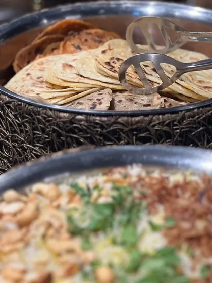 A glimpse of a Diwali buffet spread, featuring a large platter of biryani and a basket of assorted Indian breads.
