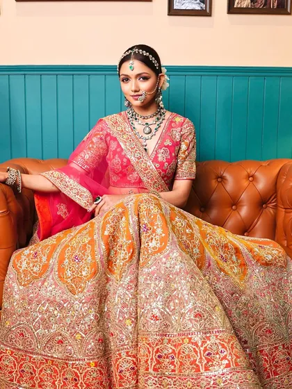 A full-length view of the 'Zehra' bride, looking regal and radiant in her vibrant pink and orange lehenga, with makeup that perfectly syncs with her attire.