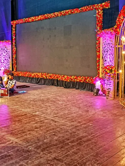 For corporate events and sangeet nights, I build stages that incorporate modern technology. This setup features a large central LED screen framed by floral decor and elegant, illuminated side panels, providing a professional backdrop for performances and presentations.