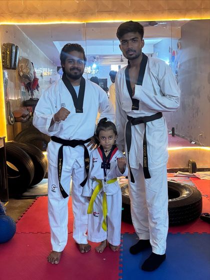 An academy champion. This young girl stands proudly between her coaches, a yellow belt who is already showing the focus of a future black belt.