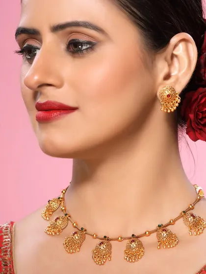 This shot showcases a traditional gold necklace with detailed motifs, perfect for a heritage jewellery brand. The model's classic look complements the timeless design of the piece.