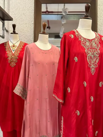A closer view of the red and pink kurtas, showcasing different embroidery patterns on the neckline and cuffs.