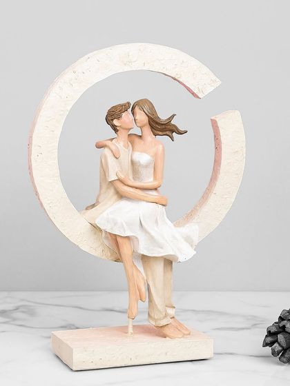 This romantic showpiece depicts a couple sitting together within a crescent moon shape. It's a sweet and tender sculpture that symbolizes love and togetherness.