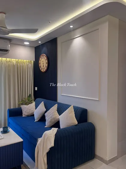 Another angle of the blue-themed living room, showing the comfortable sofa and the clean lines of the wall molding. The design is simple yet effective, creating a modern and inviting space.