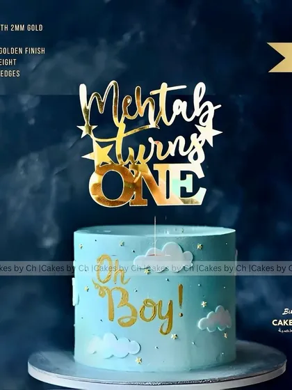 A mockup of the "Mehtab turns ONE" topper on a "Oh Boy!" themed cake, showing a perfect pairing for a little boy's first birthday.