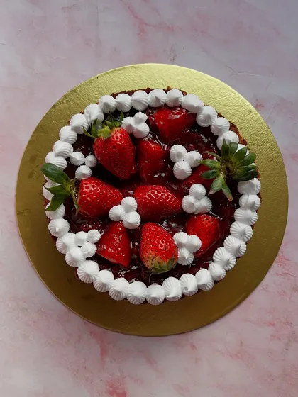 An overhead shot of our fresh strawberry cake, showcasing the generous topping of glossy strawberries and cream.