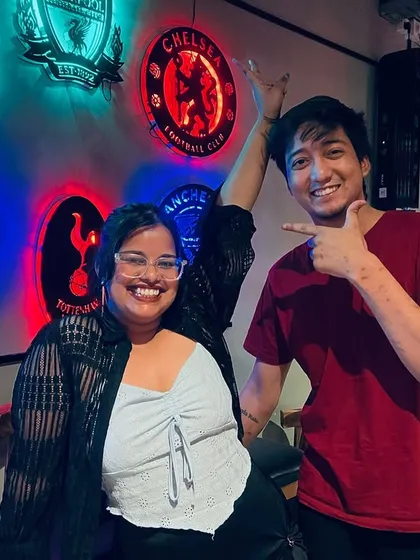 Friends posing in front of our wall of football club crests. It's a space where all passions, from sports to music, come together.