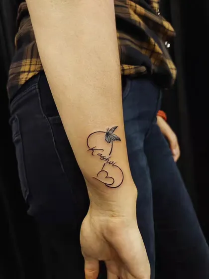A name tattoo where the initial is formed by a heart and a delicate butterfly. A creative and personal way to combine multiple symbols.