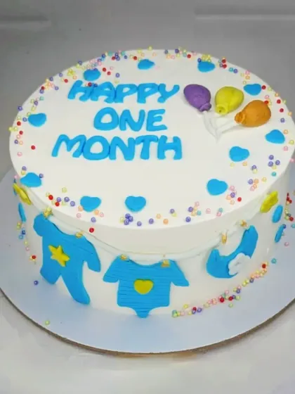 A cute cake to celebrate a baby boy's one-month milestone. This fresh pineapple cake is decorated with colorful sprinkles and tiny fondant baby clothes.