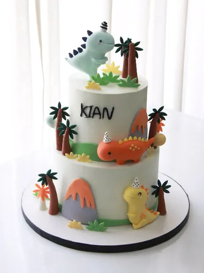 A "roarsome" dinosaur-themed cake for Kian's 1st birthday. This two-tiered cake features cute, friendly dinosaurs in a prehistoric setting.