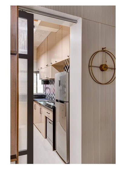A compact kitchen space for a young couple, featuring a bold geometric backsplash. A sliding fluted glass door separates it from the living area, adding a layer of texture and privacy.