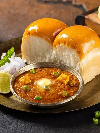 A classic Mumbai Pav Bhaji, styled with fresh garnishes and soft pav buns for Grover Sweets. I used specific lighting to emphasize the rich texture of the bhaji and the glossy butter, creating a highly appetizing hero image for their menu. This is a great example of Indian street food photography.