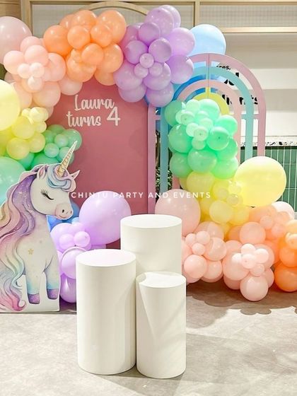 A dreamy pastel unicorn themed birthday decoration. This setup includes a large unicorn cutout, rainbow-colored balloons, and arch backdrops for a magical photo corner.