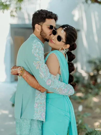A romantic embrace, with the groom kissing the bride's cheek. A sweet, candid moment from their Haldi day.
