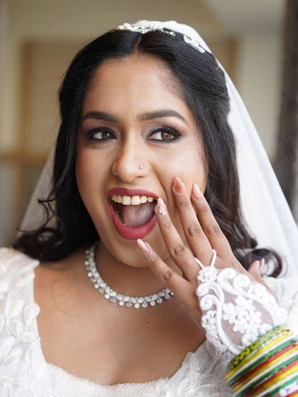 The bride's joyful and surprised expression says it all. Her makeup is glamorous yet elegant, perfect for her white wedding gown and veil.