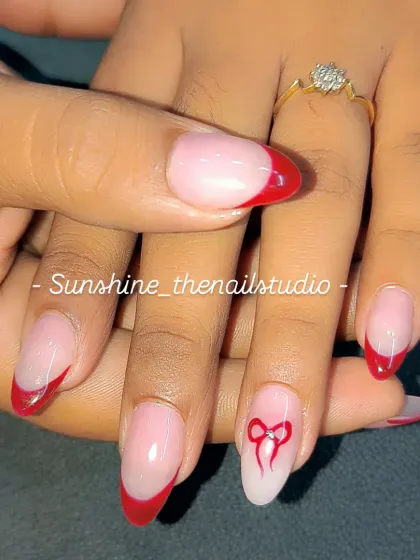 A sweet and simple red French manicure with a hand-painted bow on the ring finger.