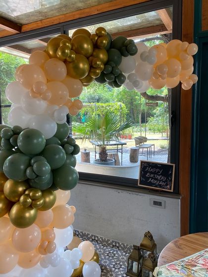 A close-up of the olive green, peach, and white balloon arrangement.
