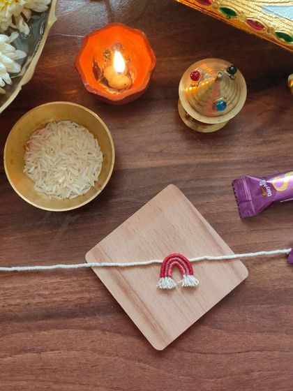 A cute and simple handmade rakhi featuring a small embroidered rainbow. This is a unique design perfect for celebrating the bond of siblings.