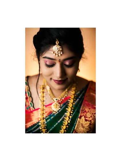 A beautiful close-up of the bride looking down, showcasing her intricate maang tikka and elegant makeup. This is a timeless and graceful bridal portrait.