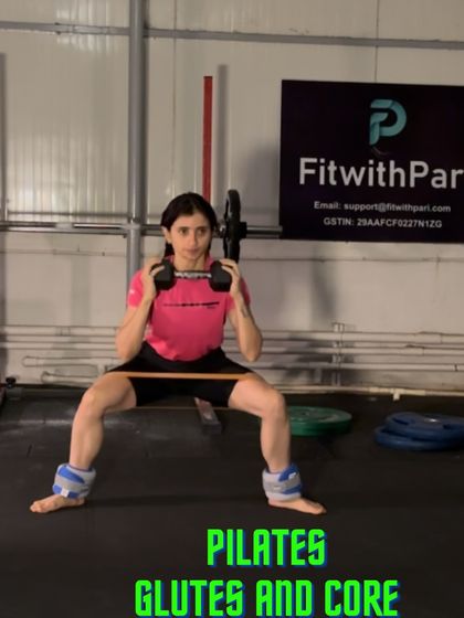 This image captures a moment from our Pilates Glutes and Core session. Using ankle weights and a resistance band, this sumo squat with a dumbbell hold intensifies the work on the lower body and core.