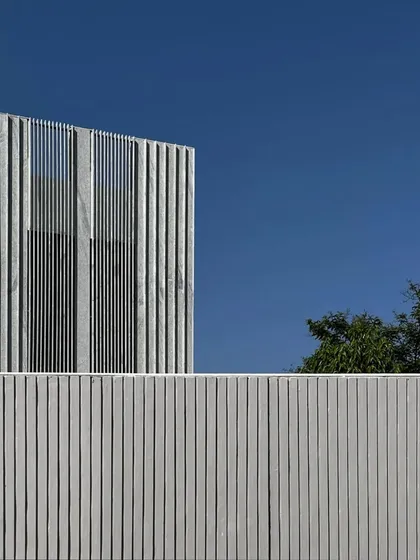 A detail of a vertically grooved stone facade against a clear blue sky. This kind of textural detail adds depth and character to a building's exterior.