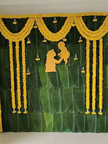 A simple and traditional Sreemantham backdrop. I used a full wall of fresh banana leaves and decorated it with marigold garlands and a mother-child motif.