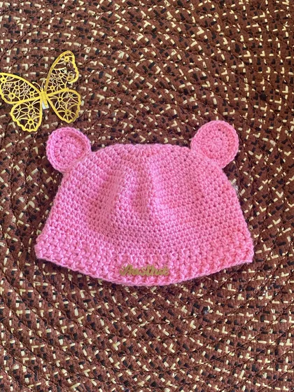 The finished handmade crochet baby beanie. This adorable pink hat with bear ears is soft and gentle, perfect for a newborn.