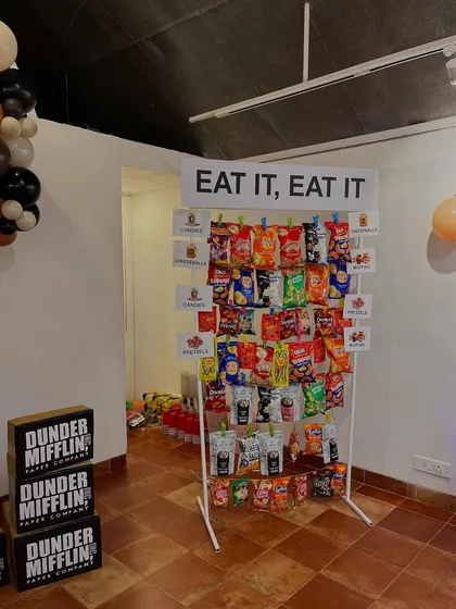 The full view of our interactive "EAT IT, EAT IT" snack wall. This installation was a highlight of the party, providing both a fun photo opportunity and a practical way to serve treats at the corporate-themed event.