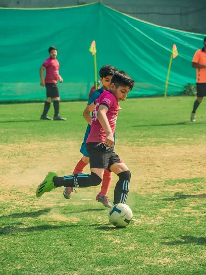 A player kicks up a cloud of dust as he strikes the ball with power.