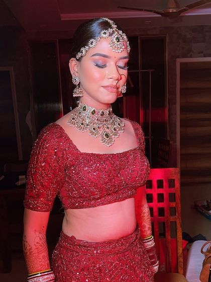 A serene moment captured before the festivities begin. This shot highlights the flawless base and the beautiful blue and silver eyeshadow that adds a modern twist to her traditional red outfit.