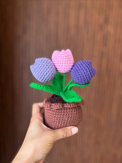 A cute little pot of three crochet tulips in purple and pink. This small arrangement is perfect for a desk, a bookshelf, or a bedside table.