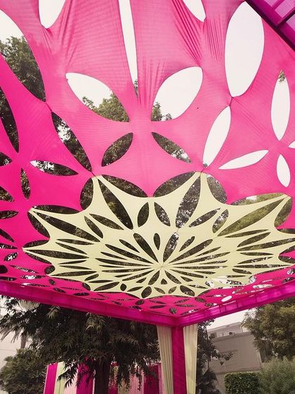 A unique laser-cut fabric canopy in hot pink creates a stunning ceiling design, casting beautiful patterns of light and shadow.