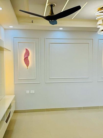 A minimalist and elegant living room wall design. It features a floating white TV console with a wood-finish niche and decorative backlit wall art.