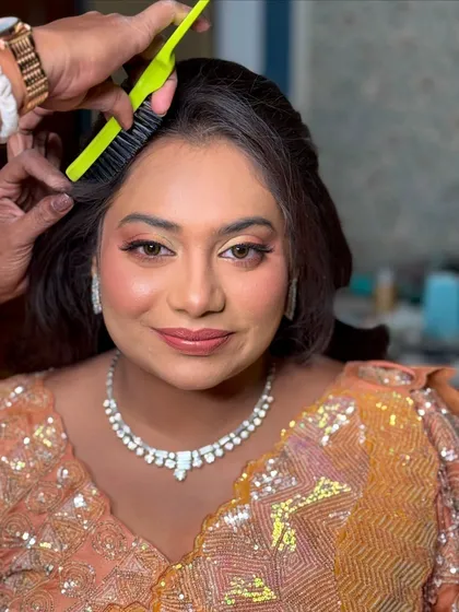 A behind the scenes moment, showing the hairstylist at work while the makeup is already flawless.