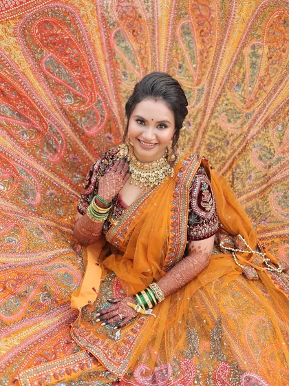 A true queen in her magnificent orange and maroon lehenga. For this bridal look, we went for a classic radiant face with defined eyes to complement the grandeur of her outfit.