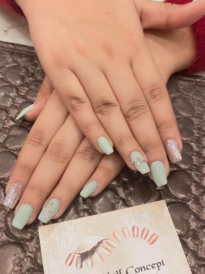 A pretty and delicate set of light green coffin nails. The look is enhanced with silver glitter accent nails and tiny 3D silver bow embellishments.