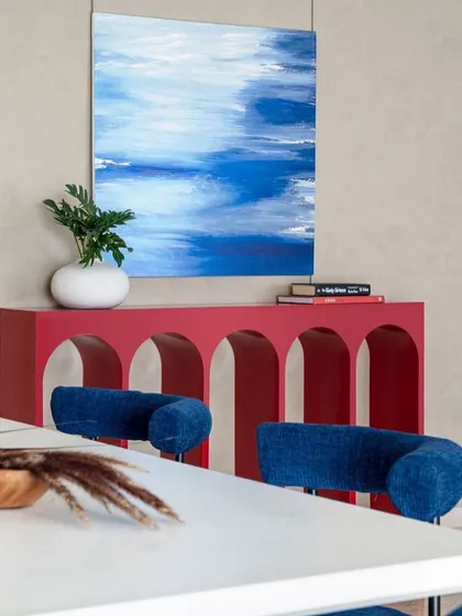 The striking combination of the red console and blue artwork against a neutral wall is a perfect example of our art-driven interior design approach.