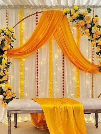 Sometimes, simplicity is the most beautiful. This chic Haldi seating arrangement uses a modern ring frame, elegantly draped with bright yellow fabric and accented with fresh floral bouquets for a clean and stylish look.