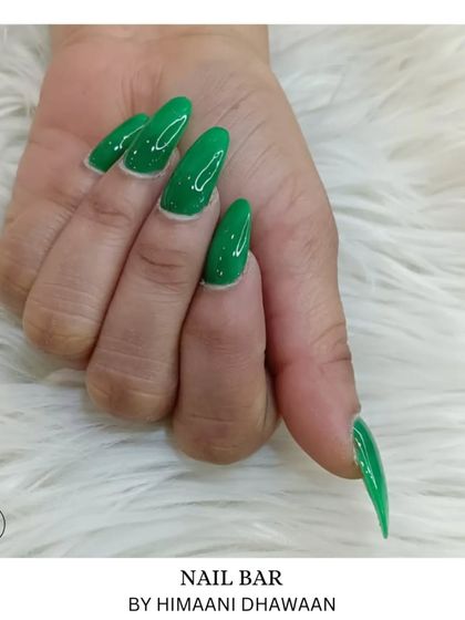A bold and vibrant glossy green manicure on long stiletto nails. A perfect way to make a statement.