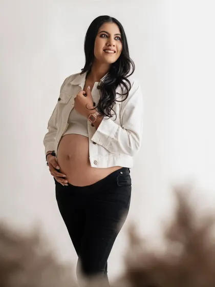 A beautiful, thoughtful portrait. The simple, modern styling with the white jacket and dark pants allows her natural pregnancy glow to be the main focus of the image.