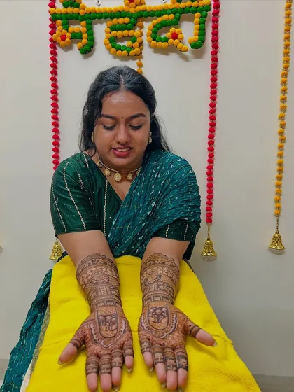 A smiling bride showing off her intricate engagement mehndi. The design features traditional patterns perfect for the occasion.