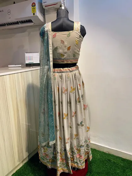 This lightweight lehenga in a subtle grey tone features delicate, colorful leaf embroidery. It's an understated and elegant rental choice for a daytime event or a smaller function.
