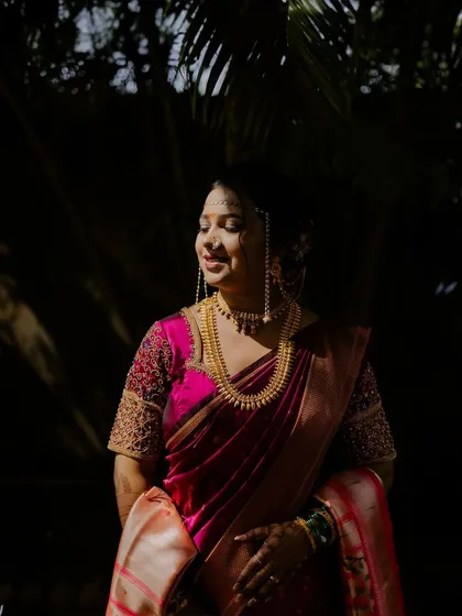 A stunning portrait of a Maharashtrian bride, with beautiful sunlight highlighting her features and traditional gold jewelry.