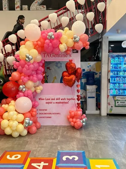Another view of the corporate Valentine's event, showing the balloon arch and the playful hopscotch floor decal. The setup creates an interactive and festive atmosphere for staff.