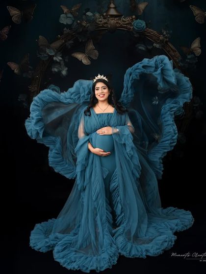 A queen on her throne. This dramatic portrait features a deep blue ruffled gown and a tiara, creating a regal and powerful image against a dark, whimsical backdrop.