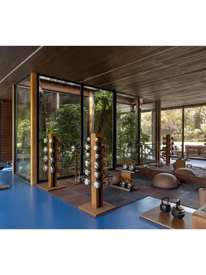 The prefabricated wooden outdoor gym, featuring glulam technology for its columns and beams. The space is surrounded by glass, offering inspiring views of the garden during workouts.