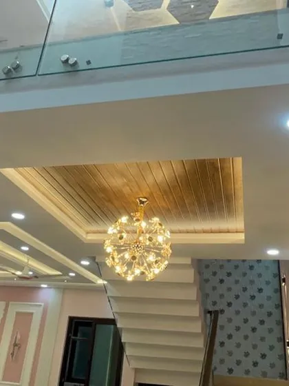 Another perspective of the double-height space, showing how the different false ceiling designs on the lower and upper levels are connected by a grand chandelier.