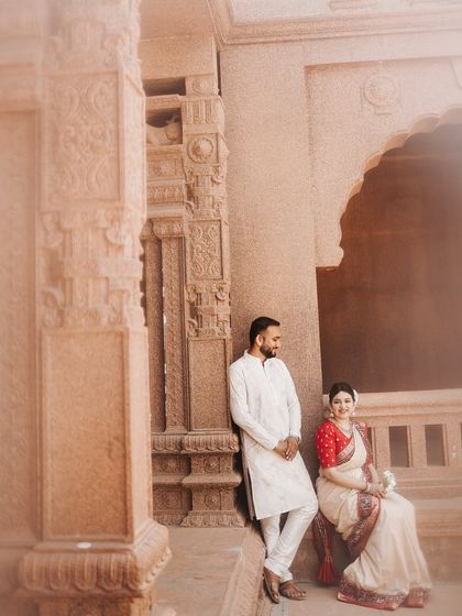 A relaxed portrait of the couple within an intricately carved stone archway. The composition uses the architectural elements to frame their quiet moment together.